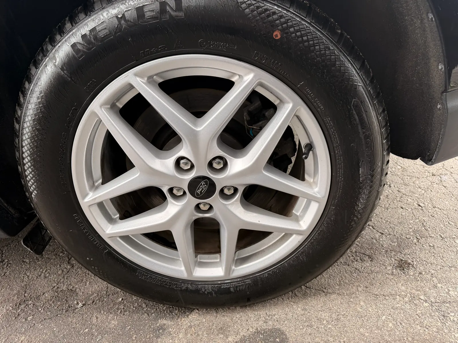 2023 Ford Edge SEL Black close-up of silver multi-spoke alloy wheel with Ford center cap and all-season tire.