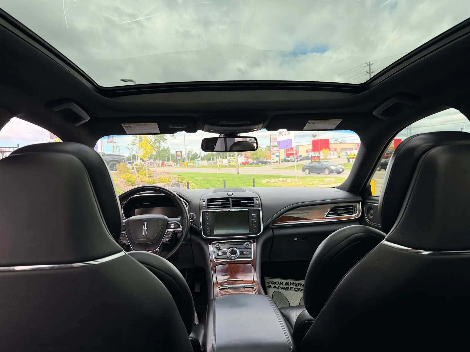 2017 Lincoln Continental Reserve Black interior view showing black leather seats, wood trim dashboard, touchscreen infotainment system, and panoramic sunroof.
