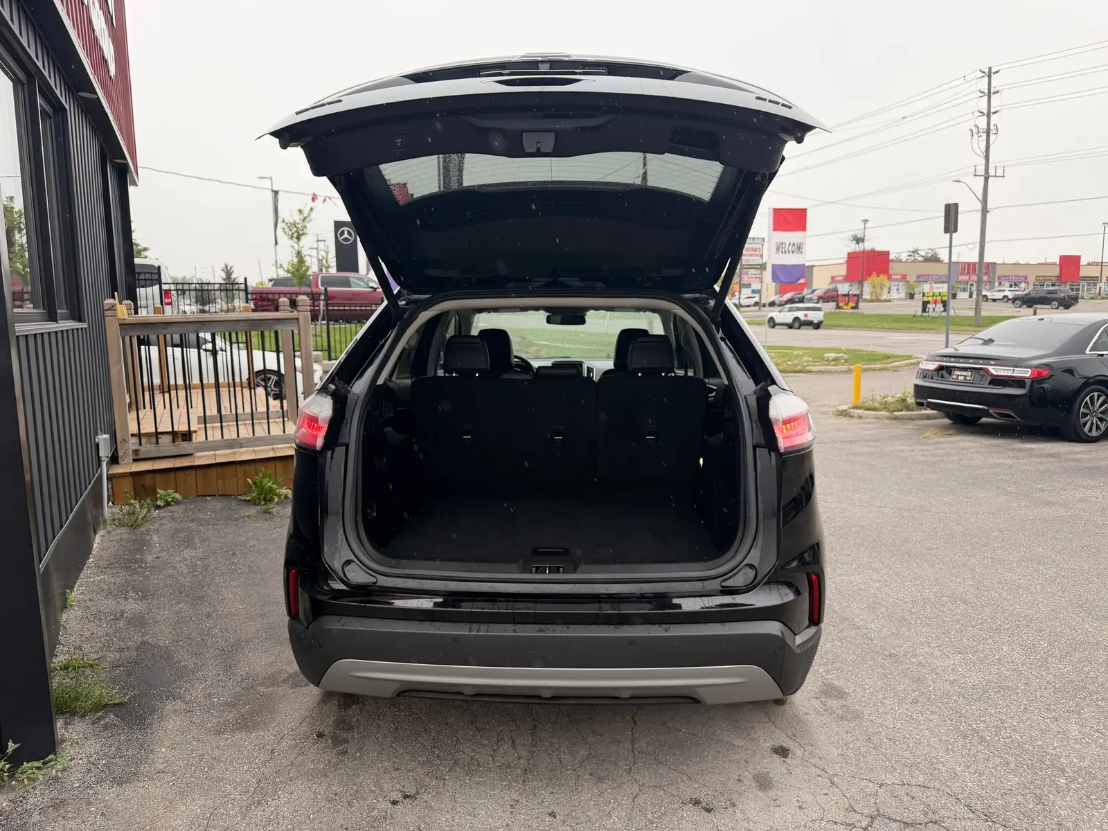 2023 Ford Edge SEL Black rear cargo area with liftgate open showing spacious trunk space in dealership lot setting.