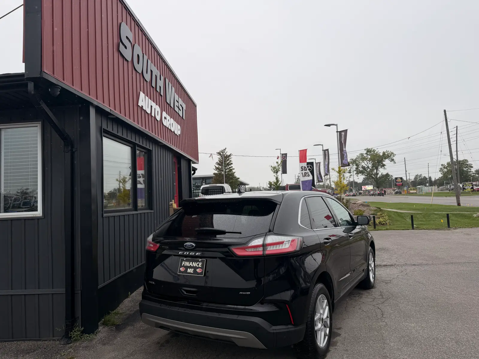 2023 Ford Edge SEL Black rear three-quarter exterior view at dealership lot with taillights visible and Finance Me plate displayed.