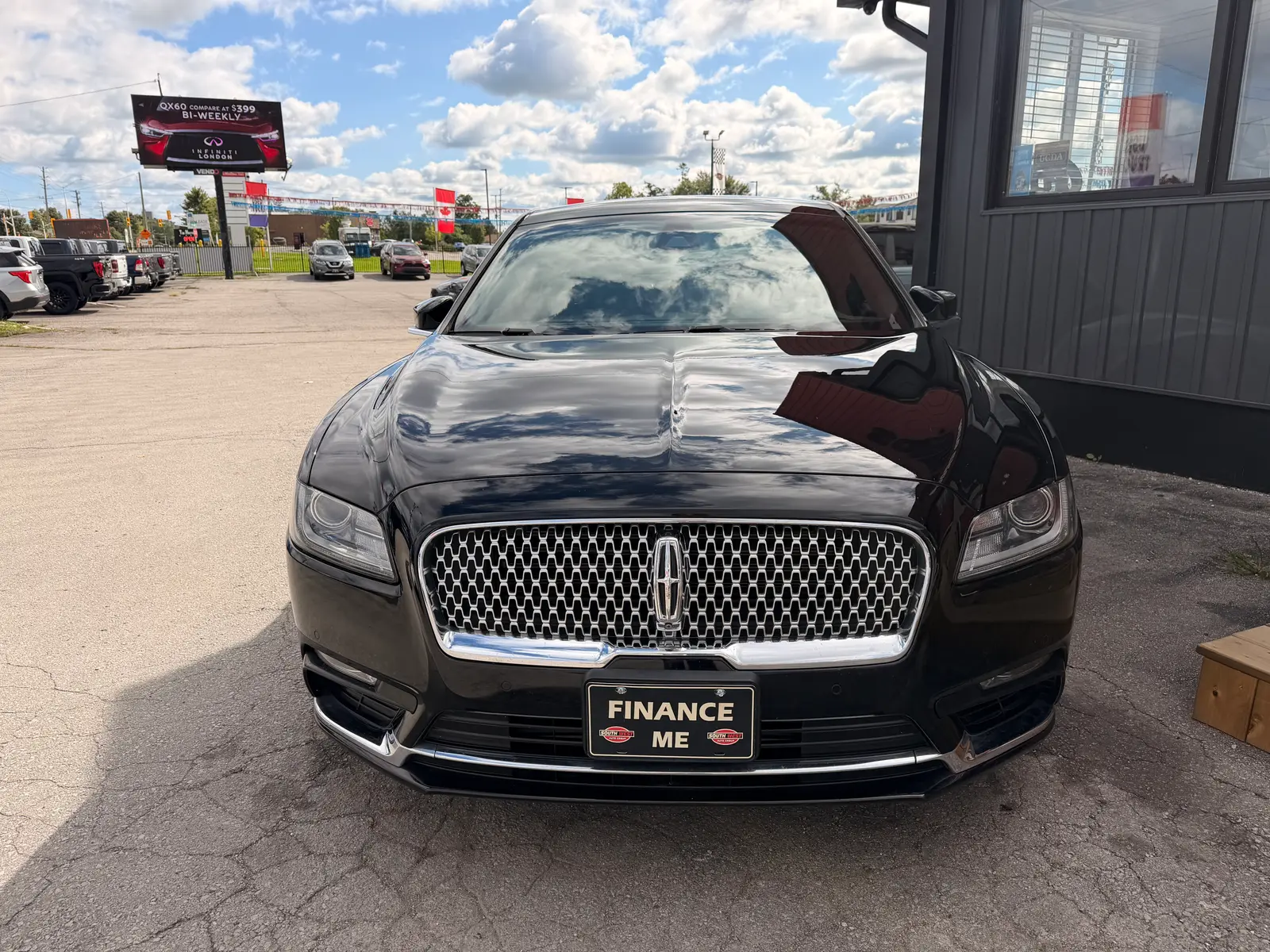2017 Lincoln Continental Reserve Black front exterior view with distinctive mesh grille and burgundy leather interior visible through open door at dealership lot.