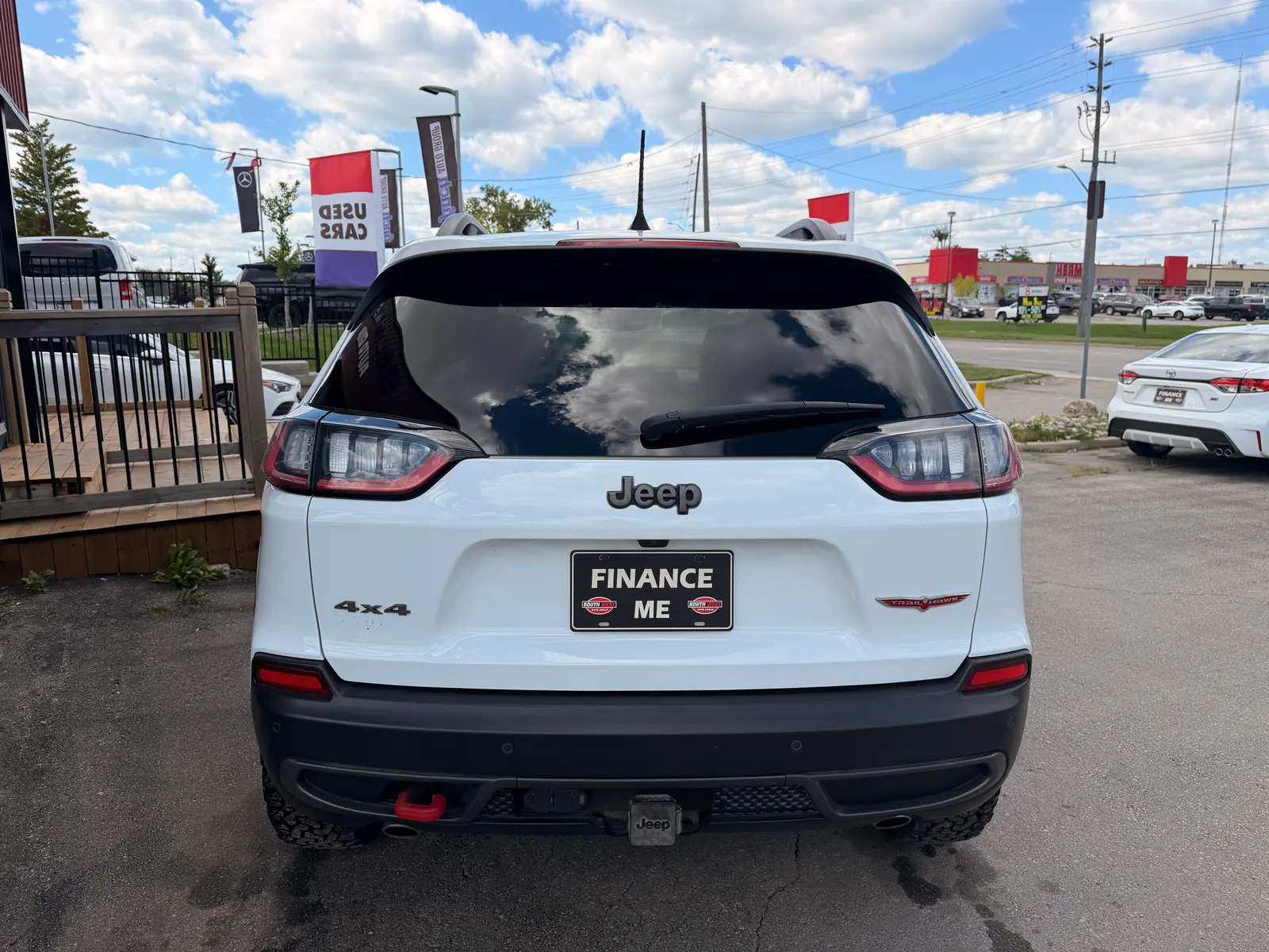 2021 Jeep Cherokee Trailhawk White rear exterior view showing taillights, badging, and "Finance Me" license plate at dealership.