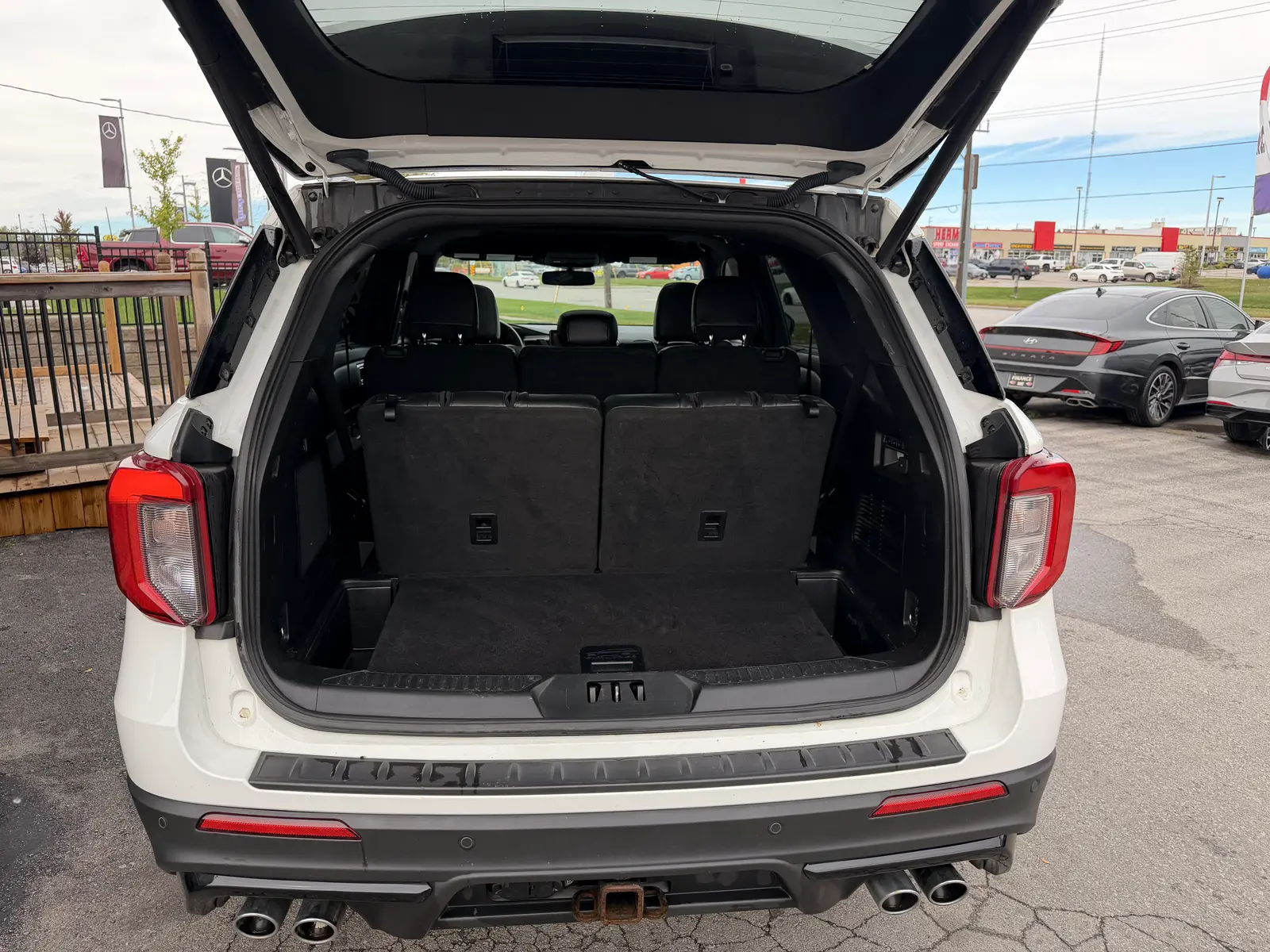 2020 Ford Explorer ST White rear cargo area with third-row seats folded flat and open liftgate in dealership lot.