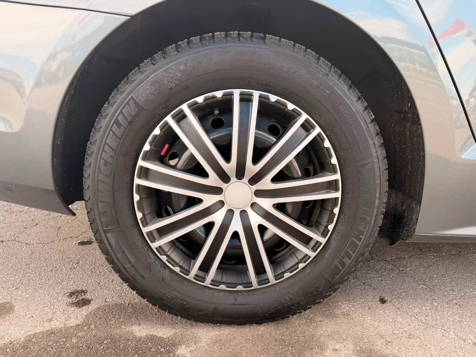 2016 Volkswagen Jetta S Gray close-up of multi-spoke alloy wheel with winter tire on asphalt.