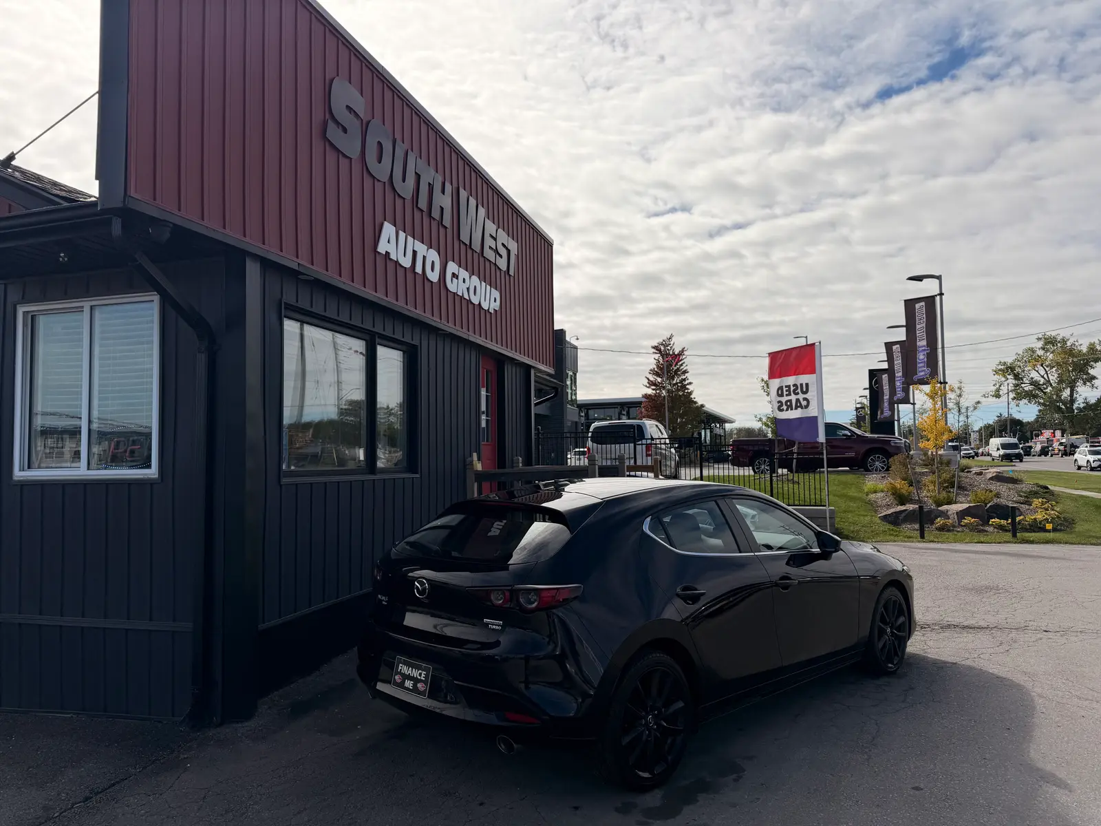 2021 Mazda Mazda3 with Premium Package Black rear three-quarter exterior view parked at dealership with dark alloy wheels visible.