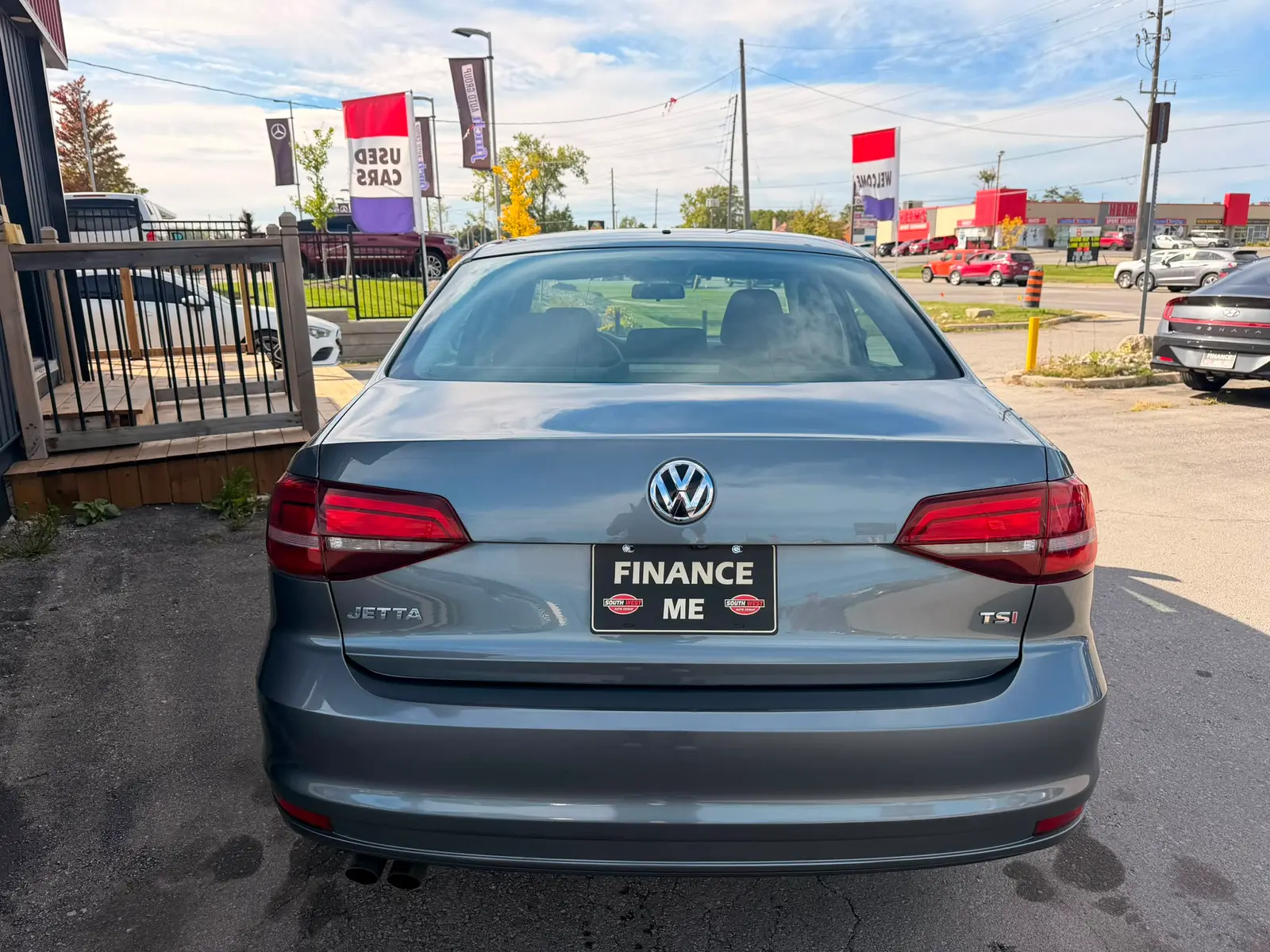 2016 Volkswagen Jetta S Gray rear exterior view with "Finance Me" license plate at dealership lot.
