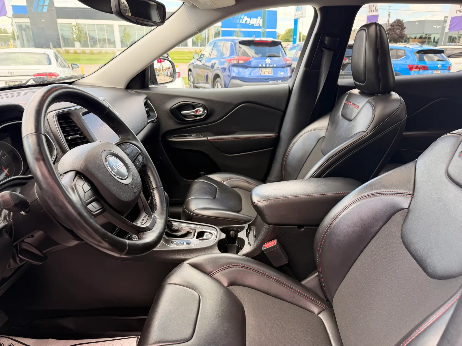 2021 Jeep Cherokee Trailhawk White interior view showing black leather seats with red stitching and steering wheel.
