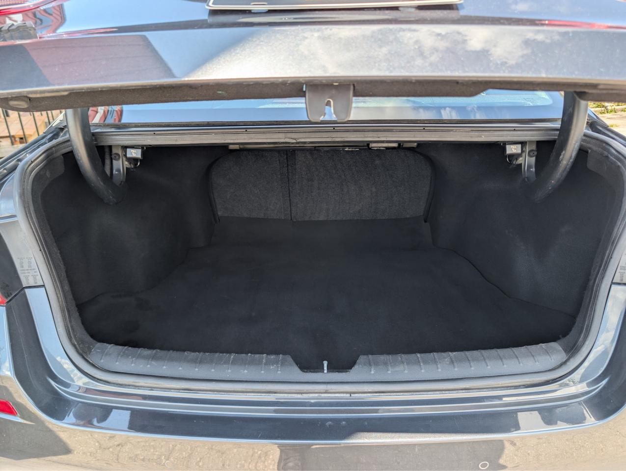 2020 Kia Optima Sedan Gray open trunk showing spacious black carpeted cargo area with fold-flat rear seats.
