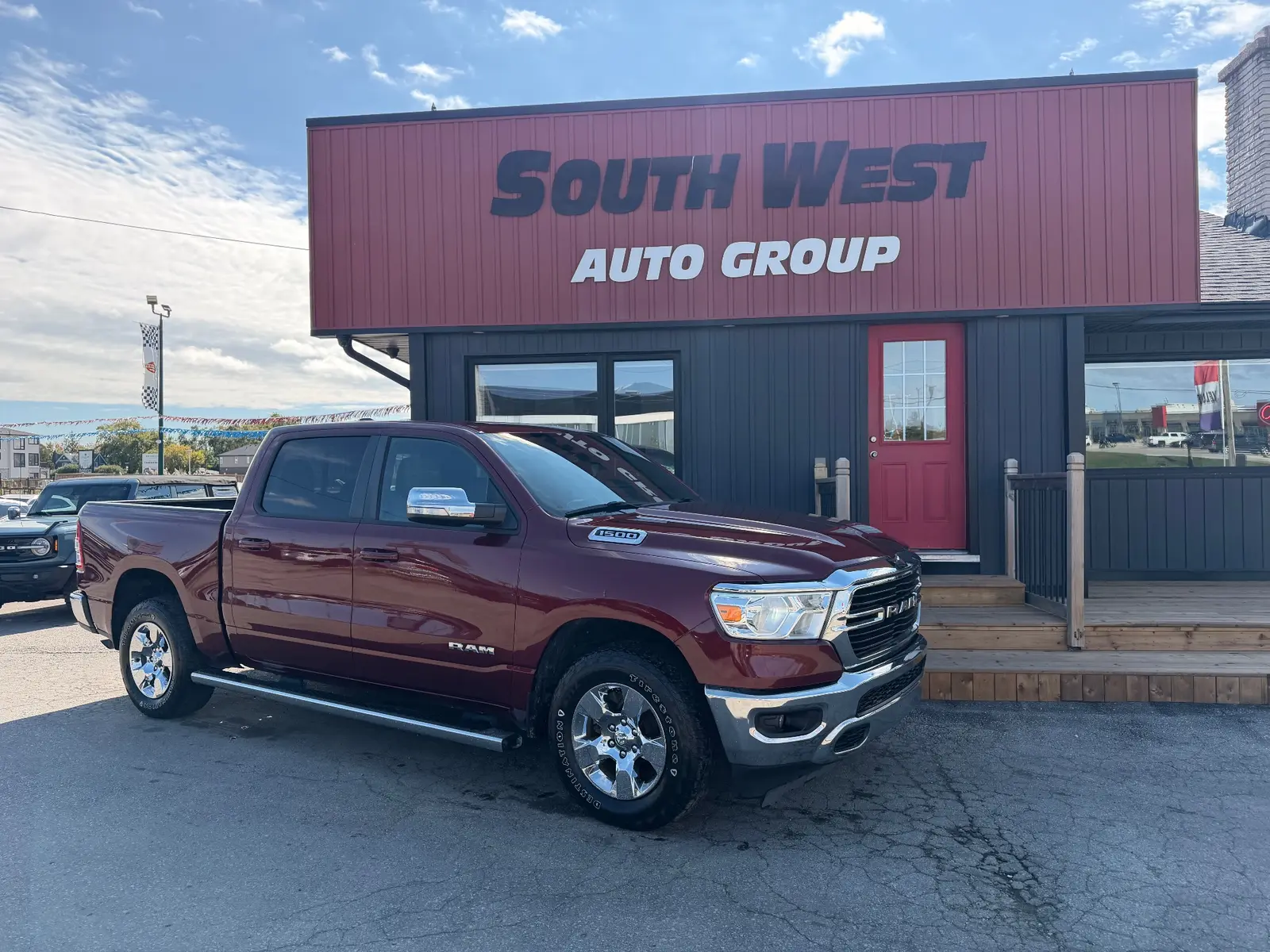 2021 Ram 1500 Big Horn, Lonestar Red front three-quarter exterior view with chrome wheels parked at dealership.