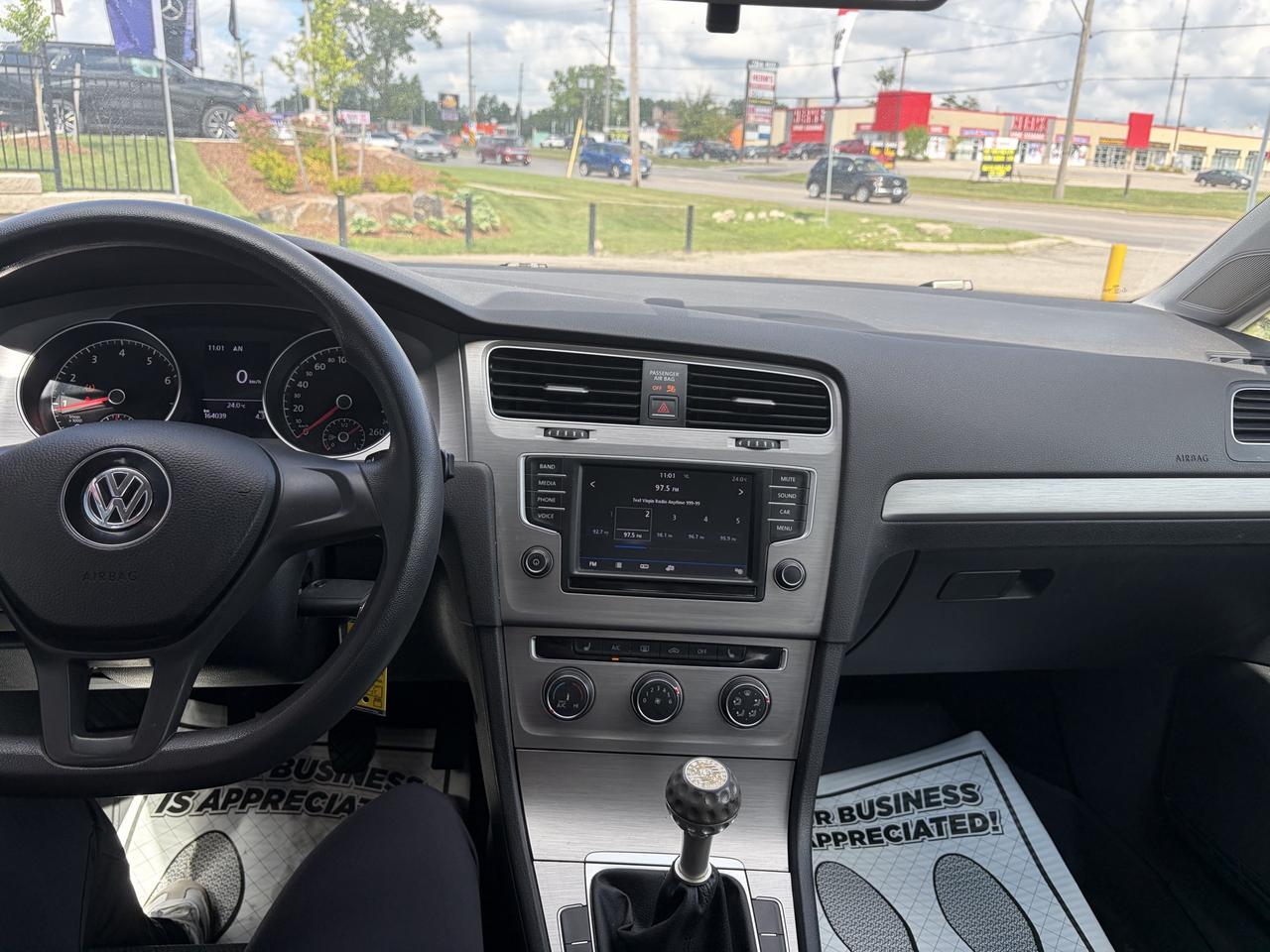 2017 Volkswagen Golf Sedan Red interior dashboard view showing infotainment screen, steering wheel, and manual transmission with business appreciation floor mats.