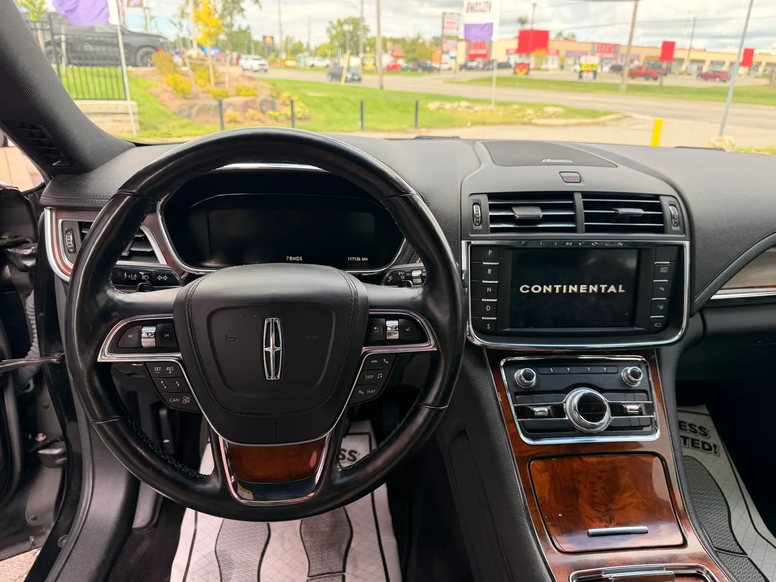 2017 Lincoln Continental Reserve Black interior dashboard view with leather-wrapped steering wheel, wood trim accents, and touchscreen infotainment display.
