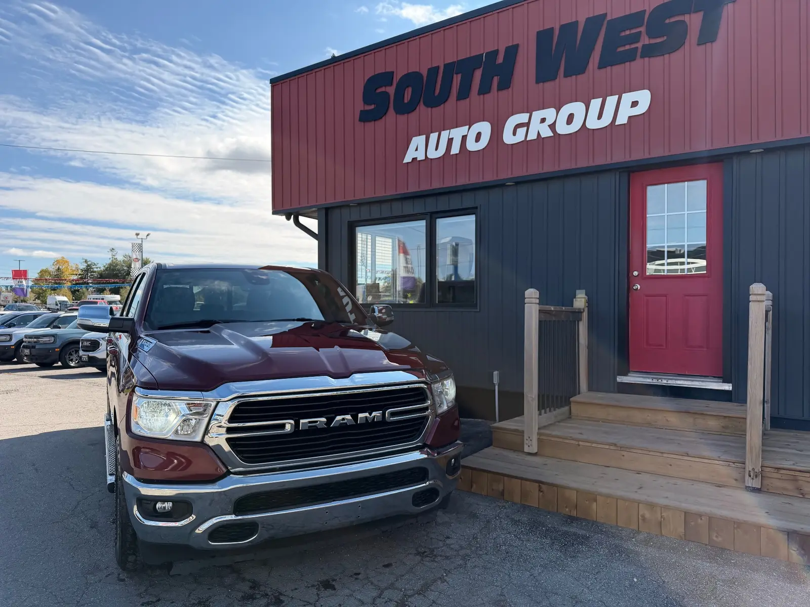 2021 Ram 1500 Big Horn, Lonestar Red front three-quarter exterior view parked at dealership in daylight.