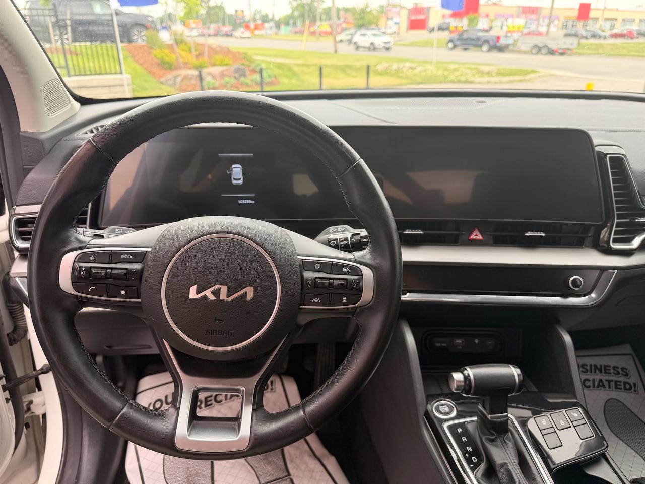 2023 Kia Sportage SUV / Crossover White interior dashboard view with leather steering wheel and infotainment screen.