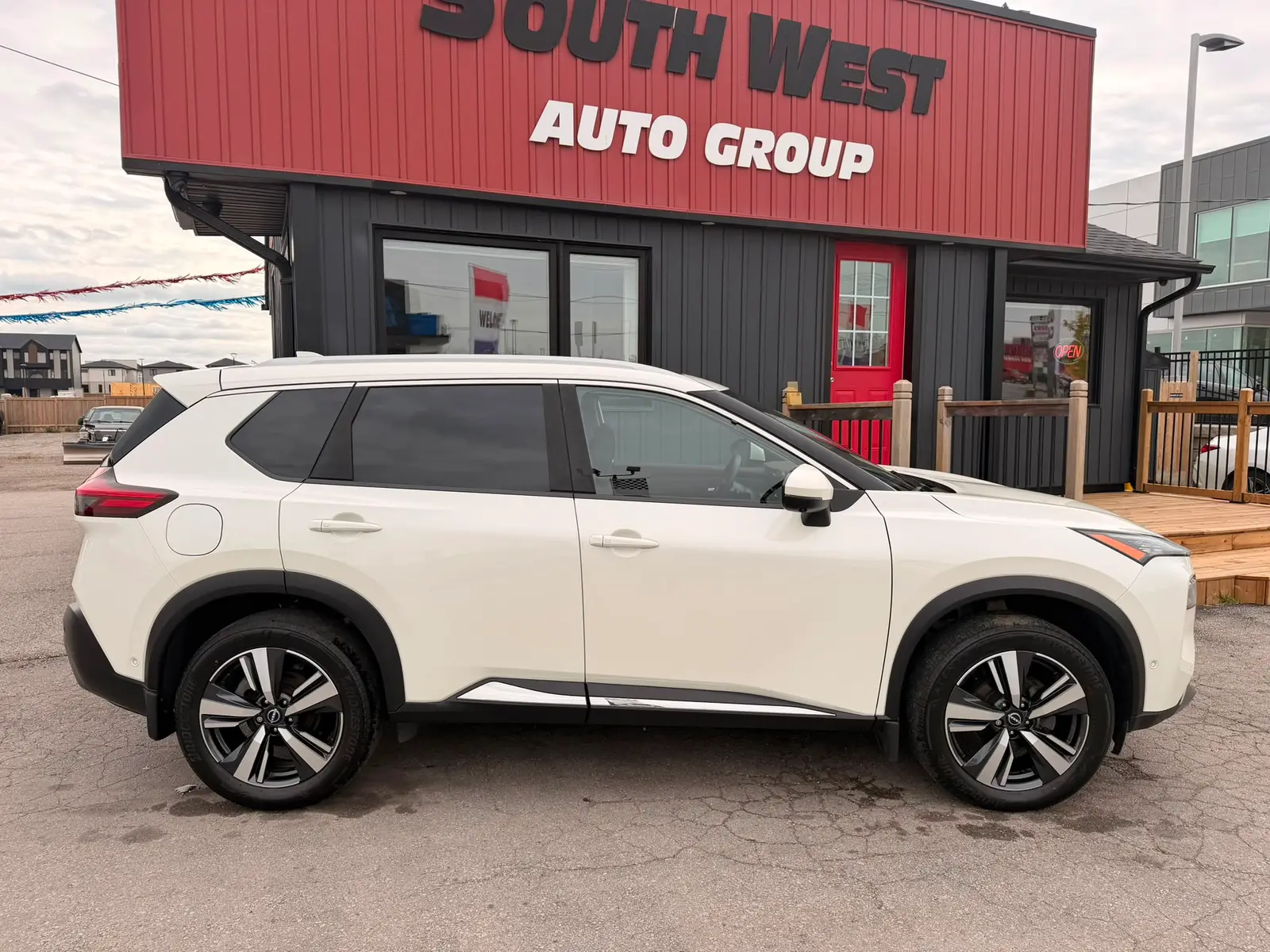 2022 Nissan Rogue SL White shown in driver-side profile view with alloy wheels at dealership lot.