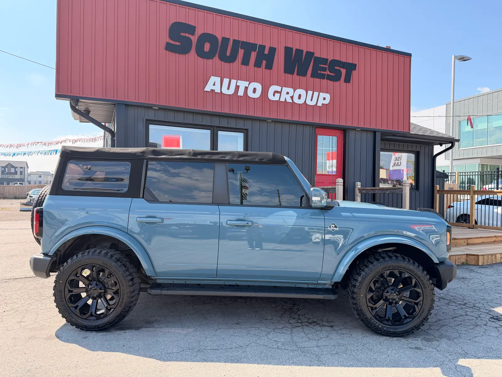 2022 Ford Bronco OUTER BANKS driver side exterior view with black custom wheels and lifted suspension parked at dealership.