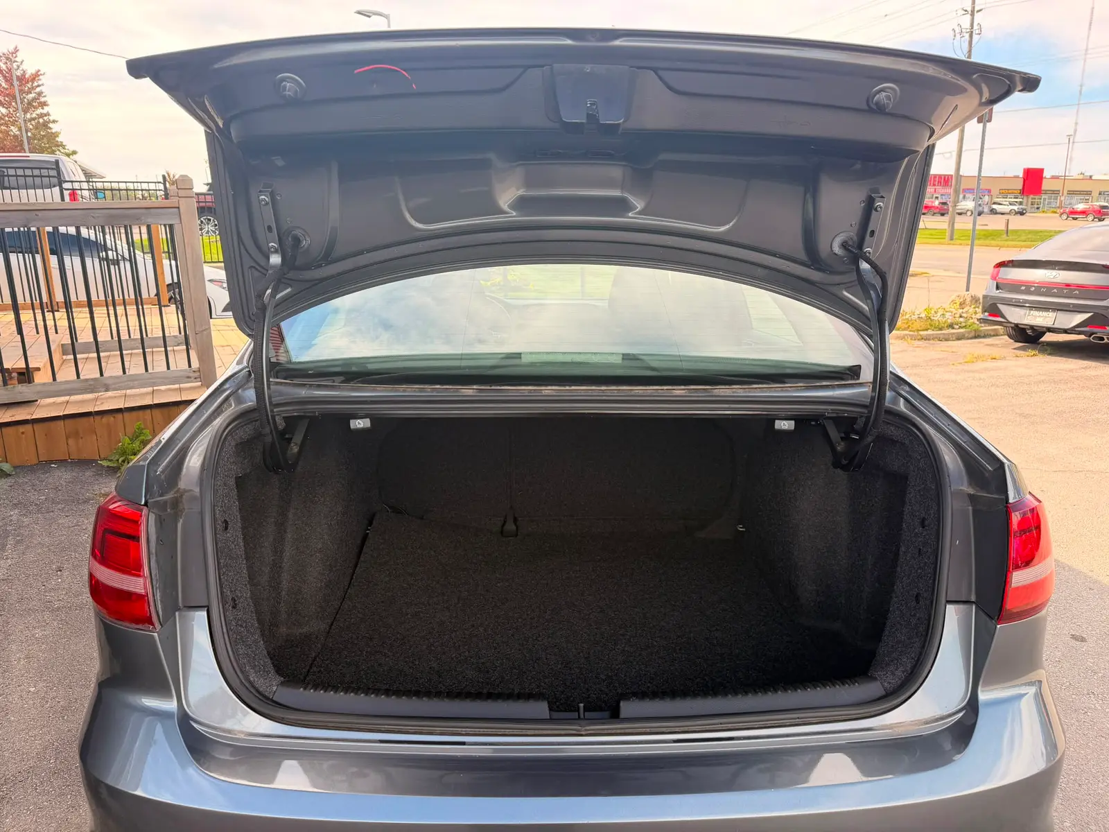 2016 Volkswagen Jetta S Gray open trunk revealing spacious black carpeted cargo area with sun shade visible.