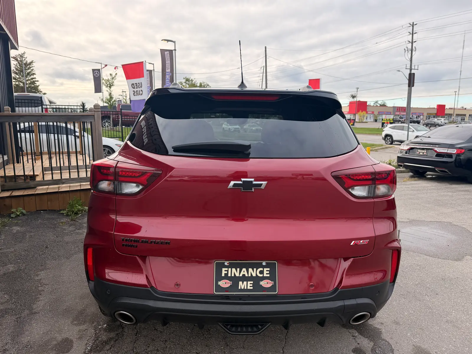 2021 Chevrolet Trailblazer RS Red rear exterior view with dual exhaust and "Finance Me" license plate at dealership.