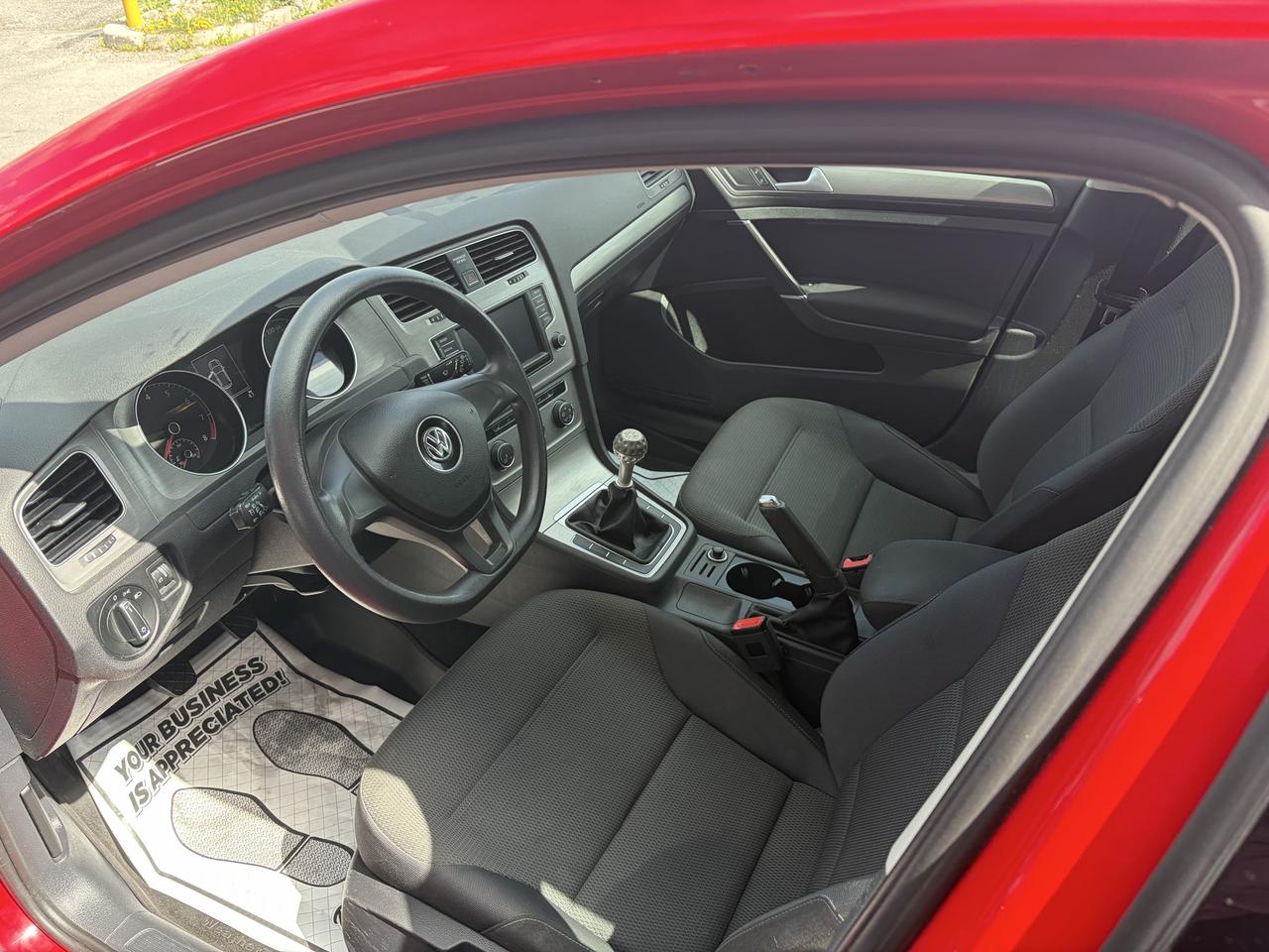 2017 Volkswagen Golf Sedan Red interior view showing black cloth seats, steering wheel, dashboard, and manual transmission shifter.