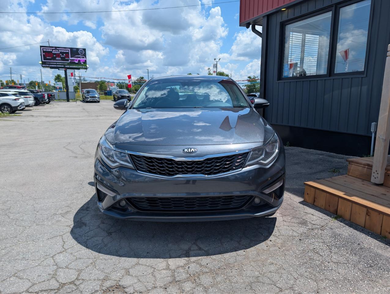 2020 Kia Optima Sedan Gray front exterior view parked at dealership lot with distinctive grille design visible.